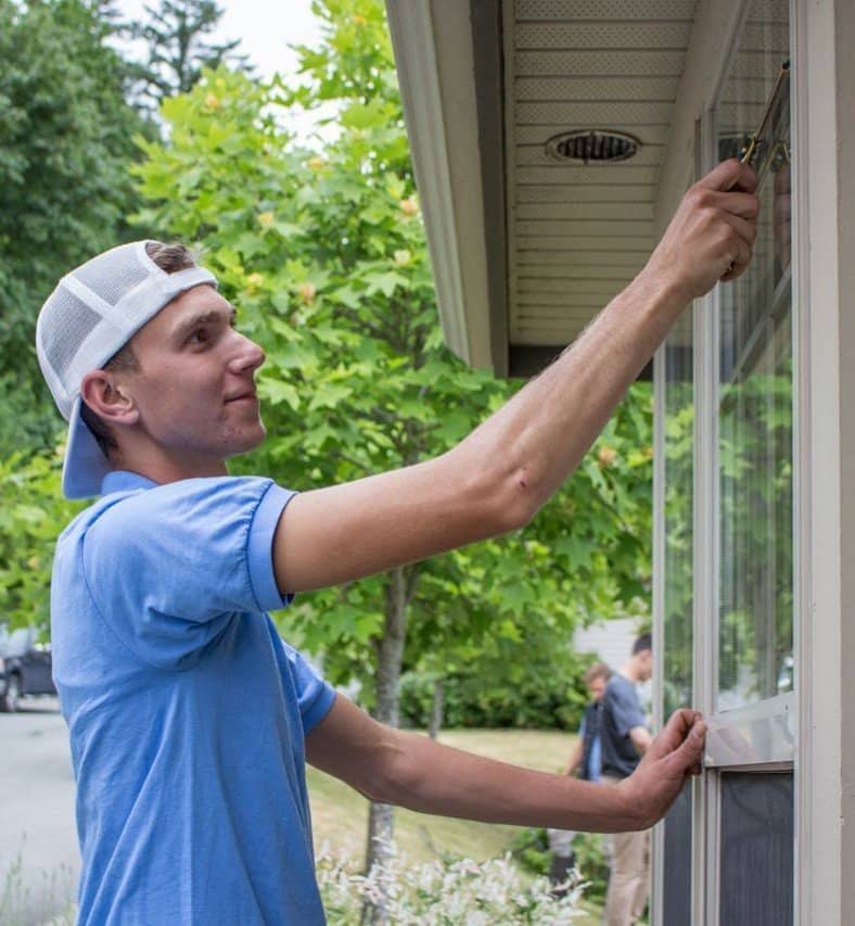 A Man is wearing a light blue polo shirt while cleaning windows.