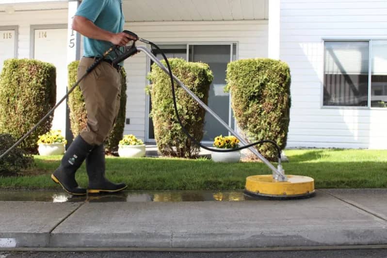 Man holding a yellow High-pressure washer to clean the walkways.